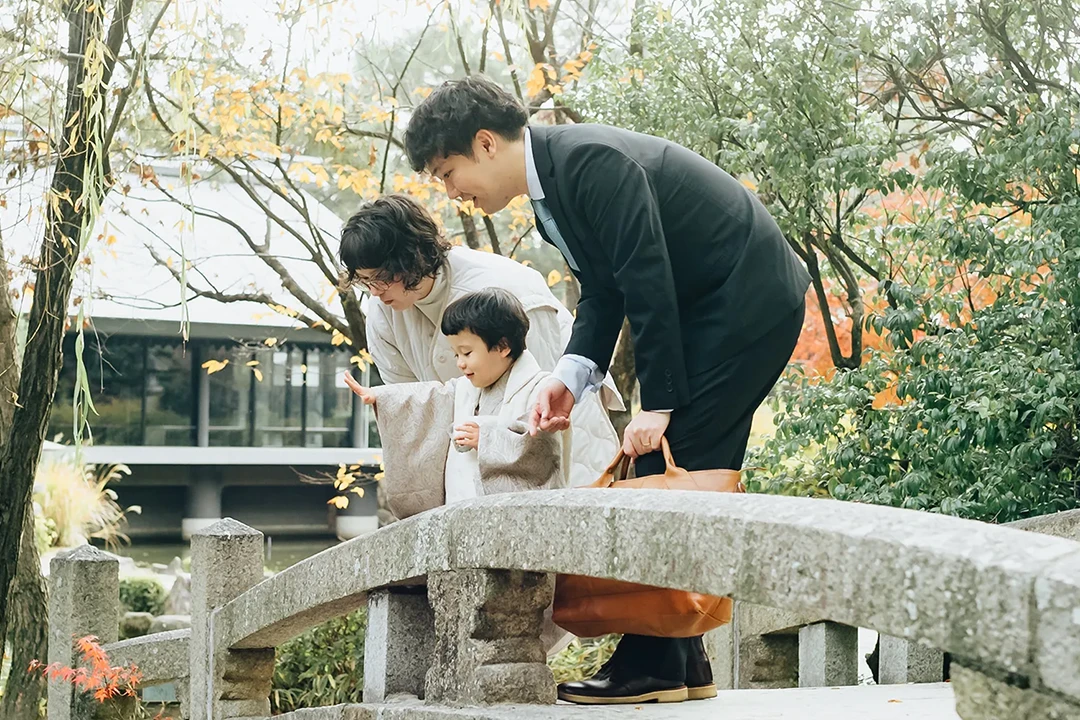 神社の石橋から川を覗き込んでいる親子